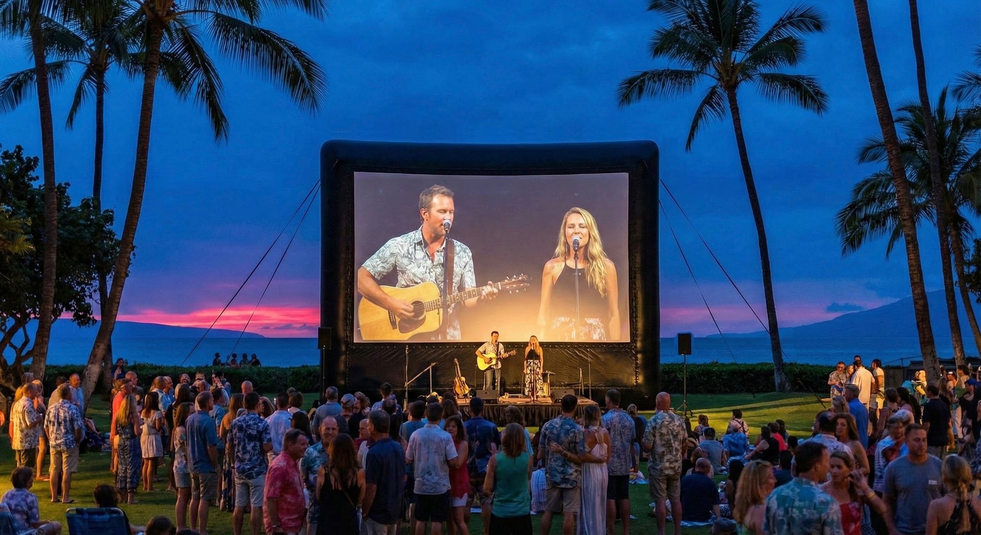 A 25-foot Open Air Cinema Elite screen on a beach lawn with an audience in front of it